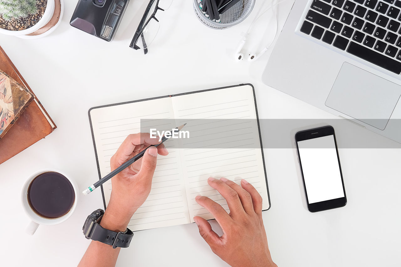 Cropped hands of person writing in diary on desk