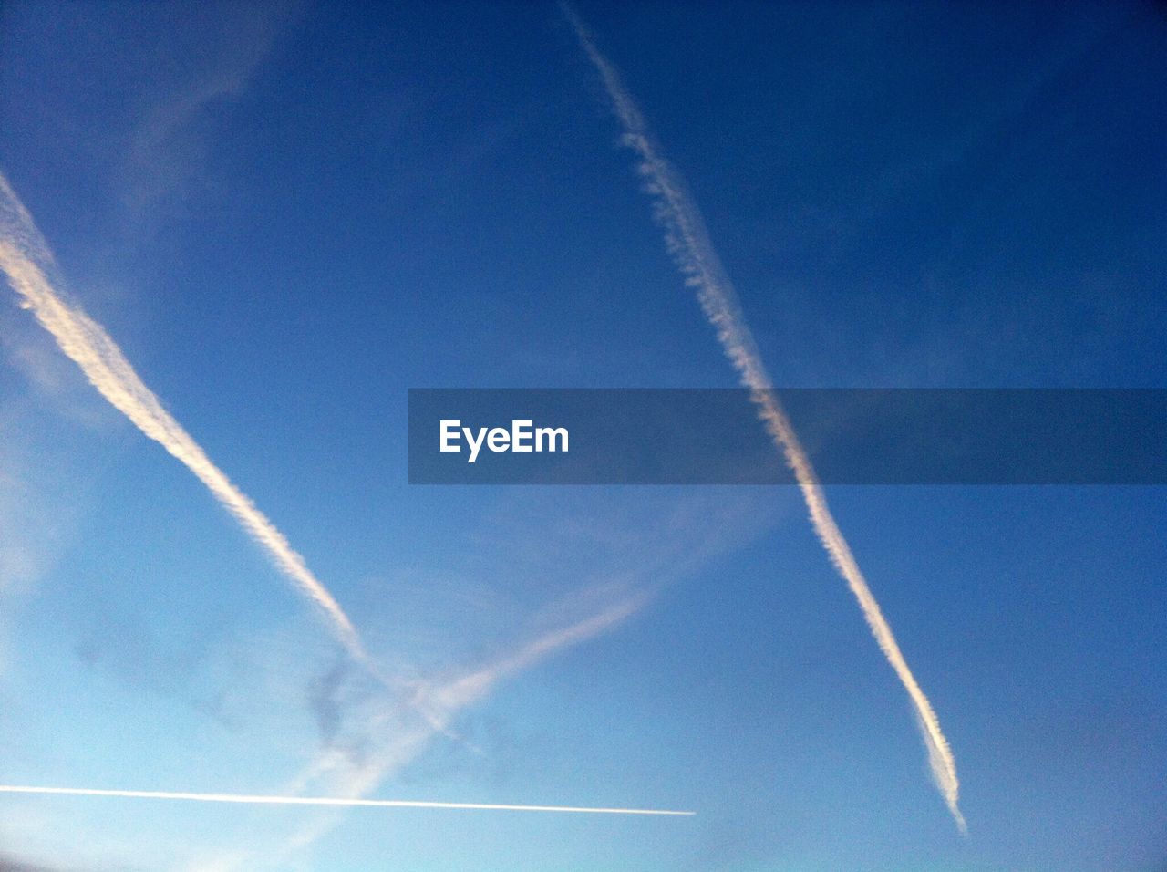 LOW ANGLE VIEW OF VAPOR TRAILS IN BLUE SKY