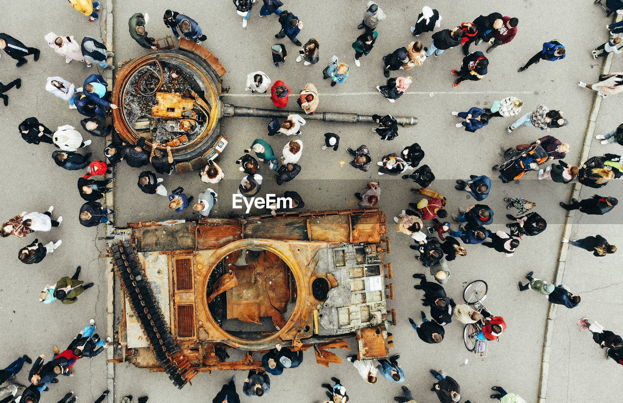 High angle view of people walking on street next to the wrecked russian fascist equipment