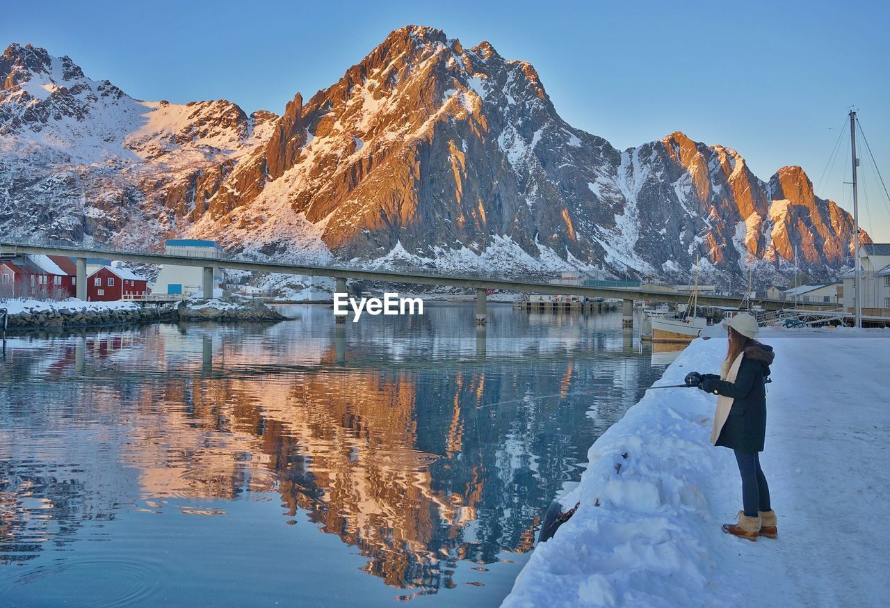 Side view of woman fishing in river during winter