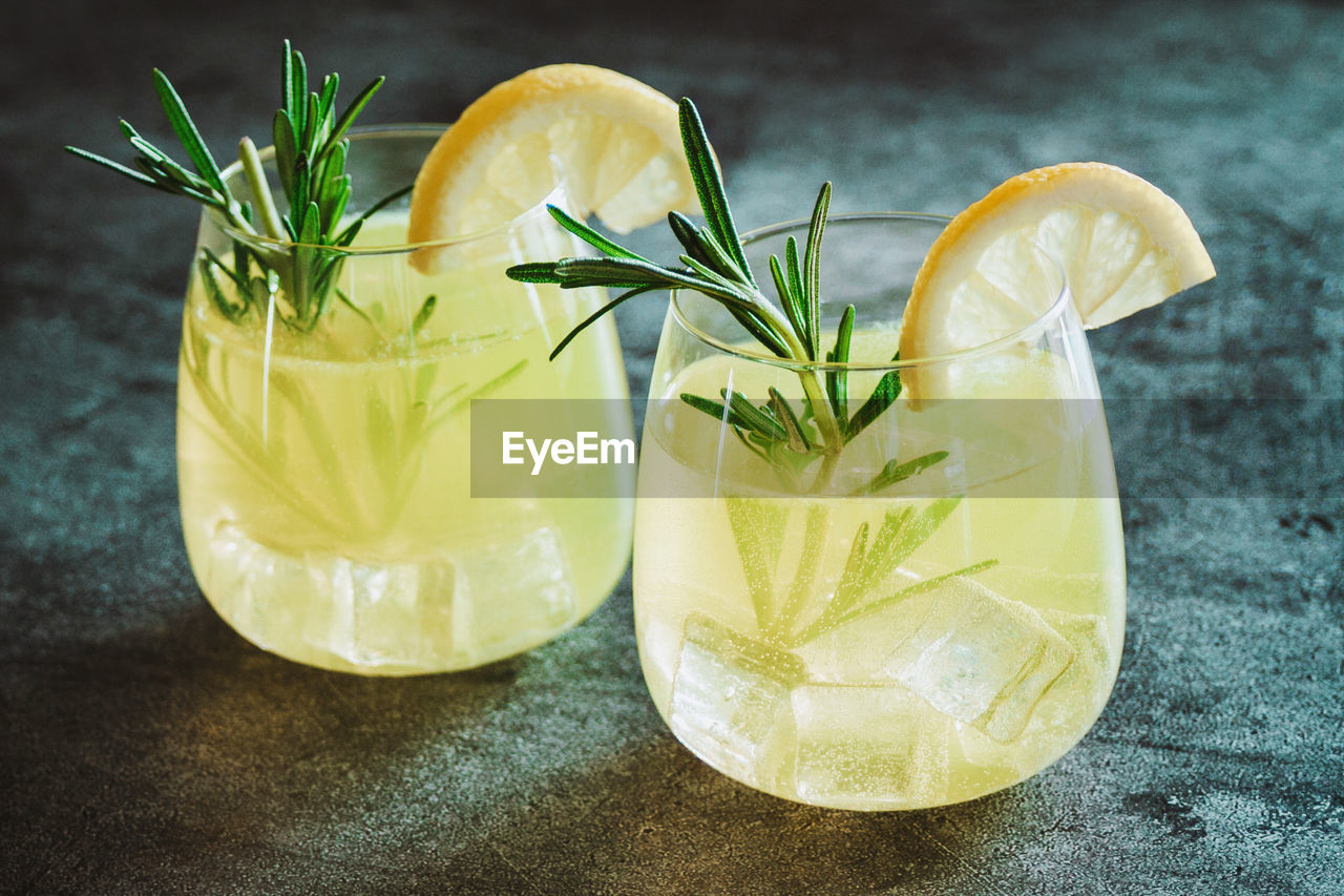 Cold cocktail, lemonade with lemon sliced, rosemary plant on dark concrete background. drink photo