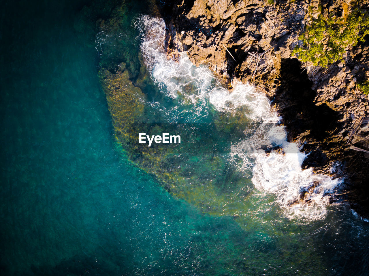 HIGH ANGLE VIEW OF ROCK FORMATIONS ON SEA