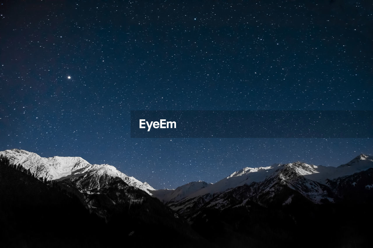 Scenic view of snowcapped mountains against sky at night