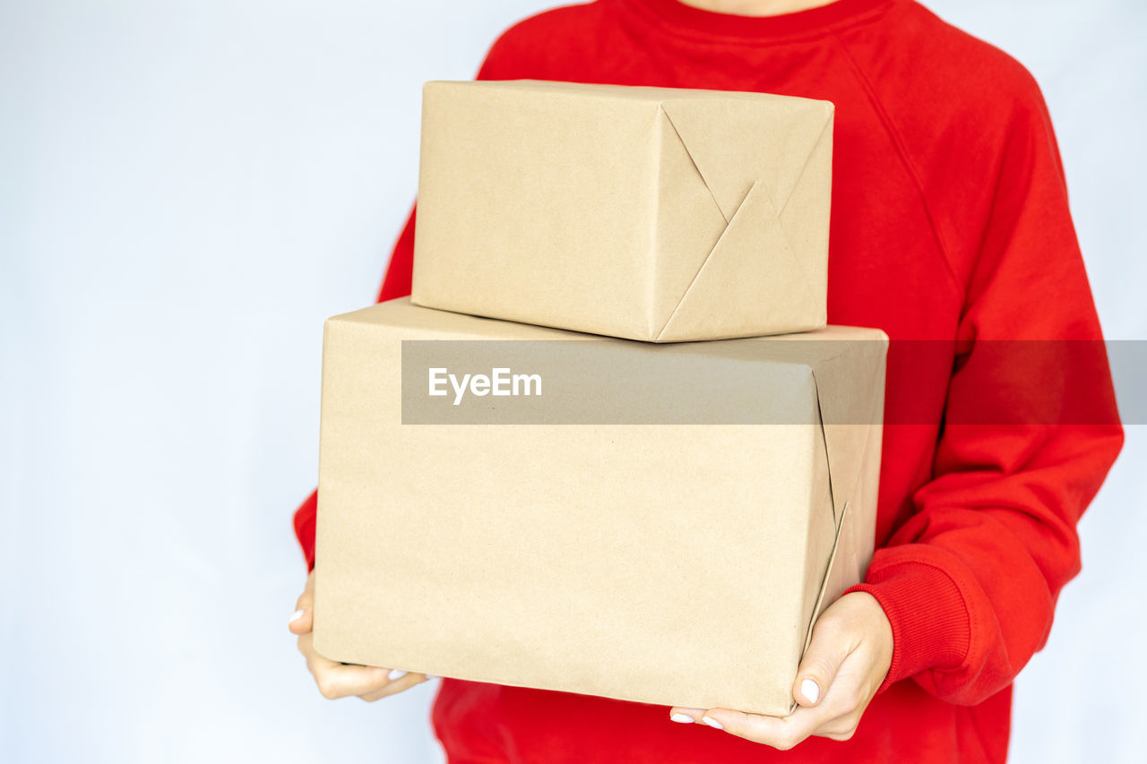 Express delivery. a young woman in a red sweatshirt holds a cardboard boxes. online shopping.