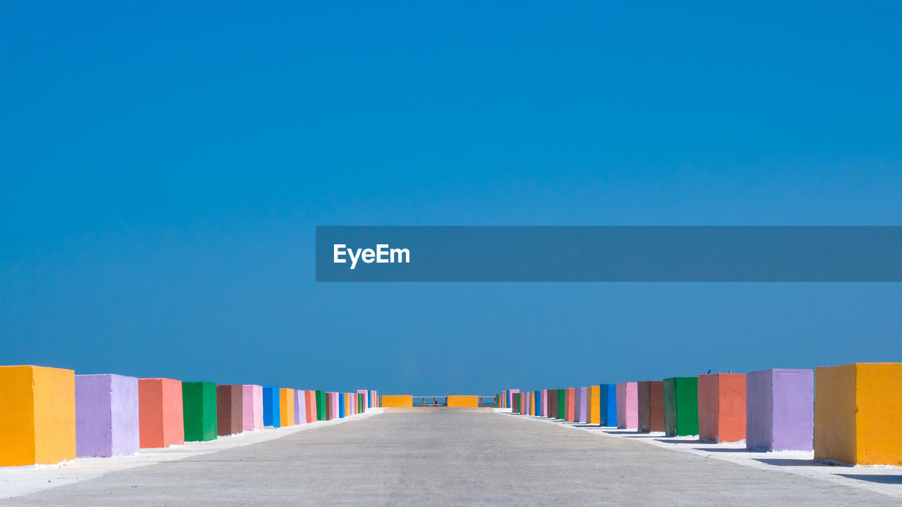 The cement bridge extends into the sea. with colorful barrier panels in the blue sky