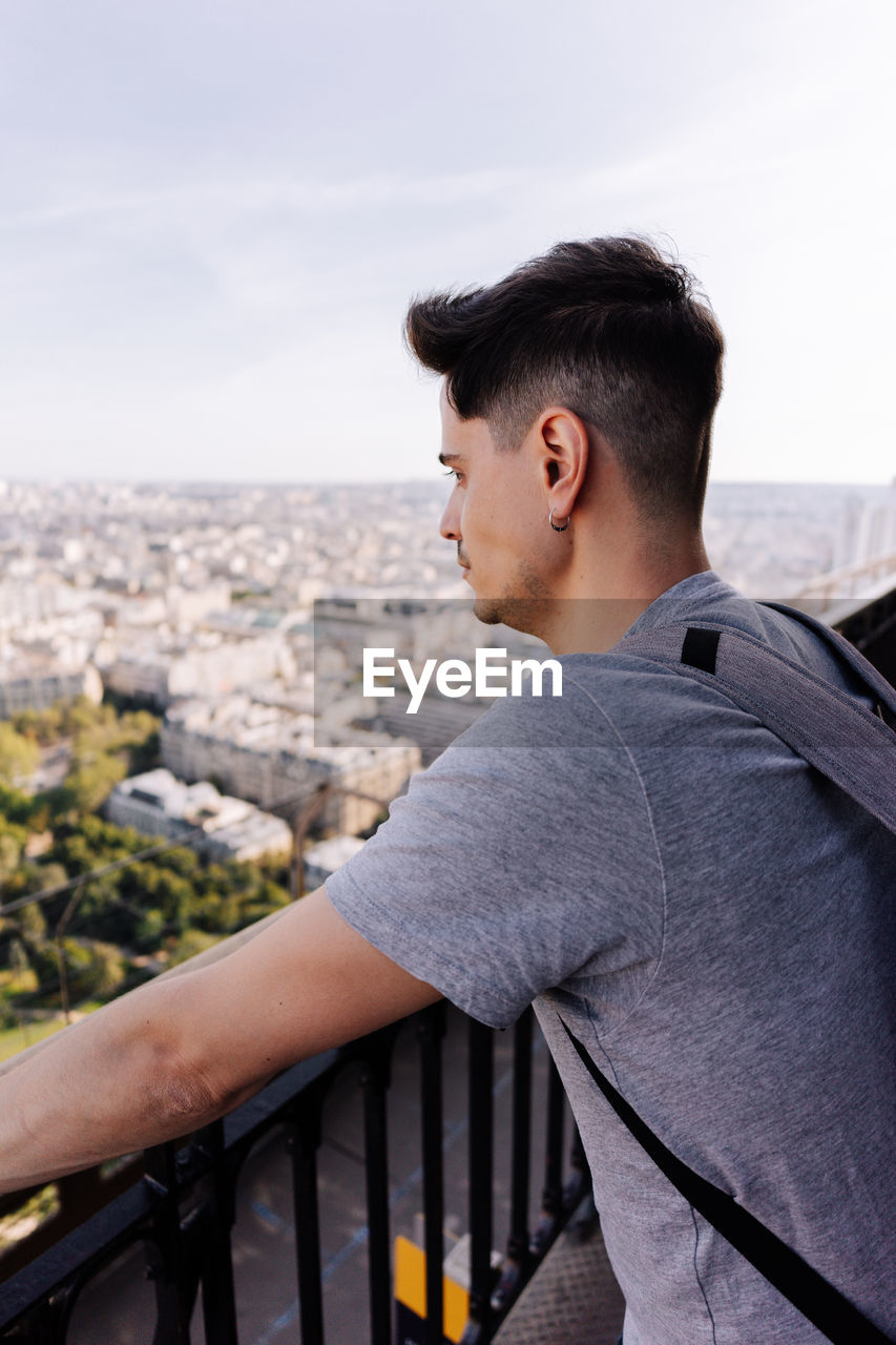 SIDE VIEW OF MAN LOOKING AT CITYSCAPE