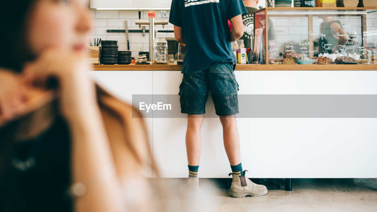 REAR VIEW OF FRIENDS STANDING IN KITCHEN