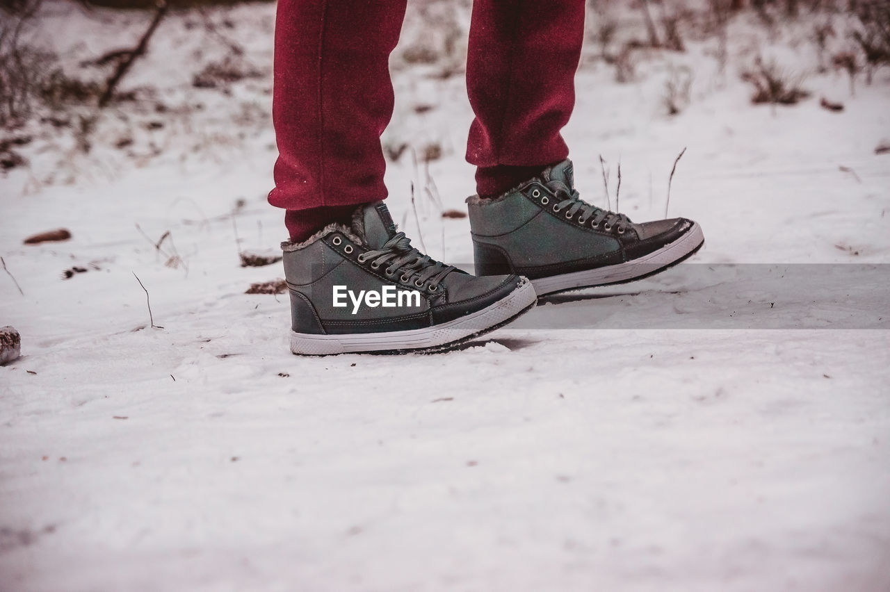 The legs of a person standing on the snow path at winter close up