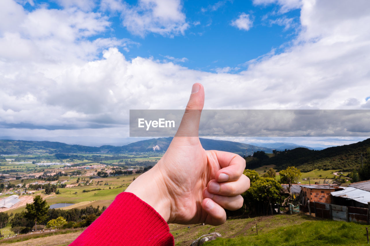 Person showing thumbs up against sky