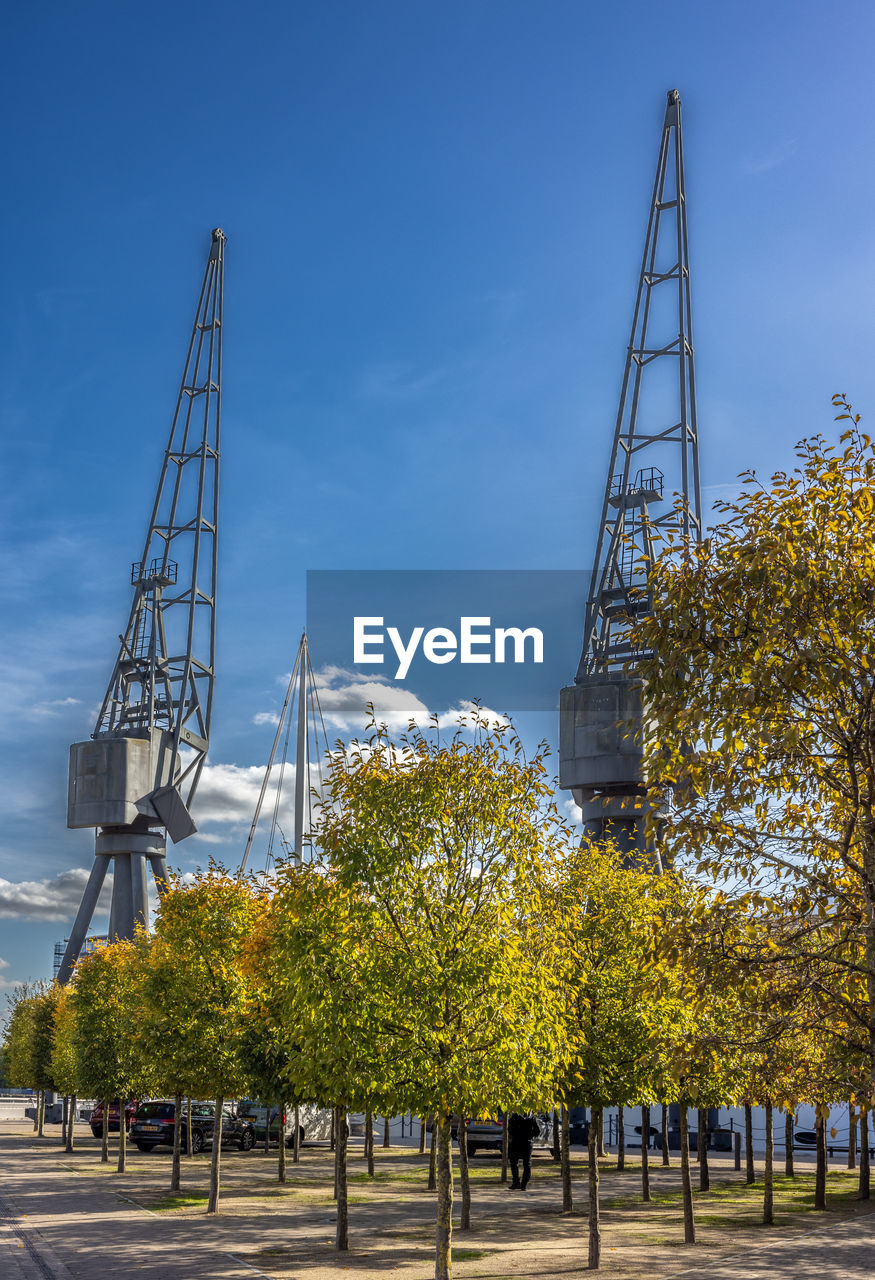 sky, architecture, tree, plant, nature, built structure, city, urban area, park, landmark, transportation, cityscape, outdoors, blue, industry, no people, day, business finance and industry, cloud, downtown, building exterior, tower, travel, construction industry, travel destinations, street