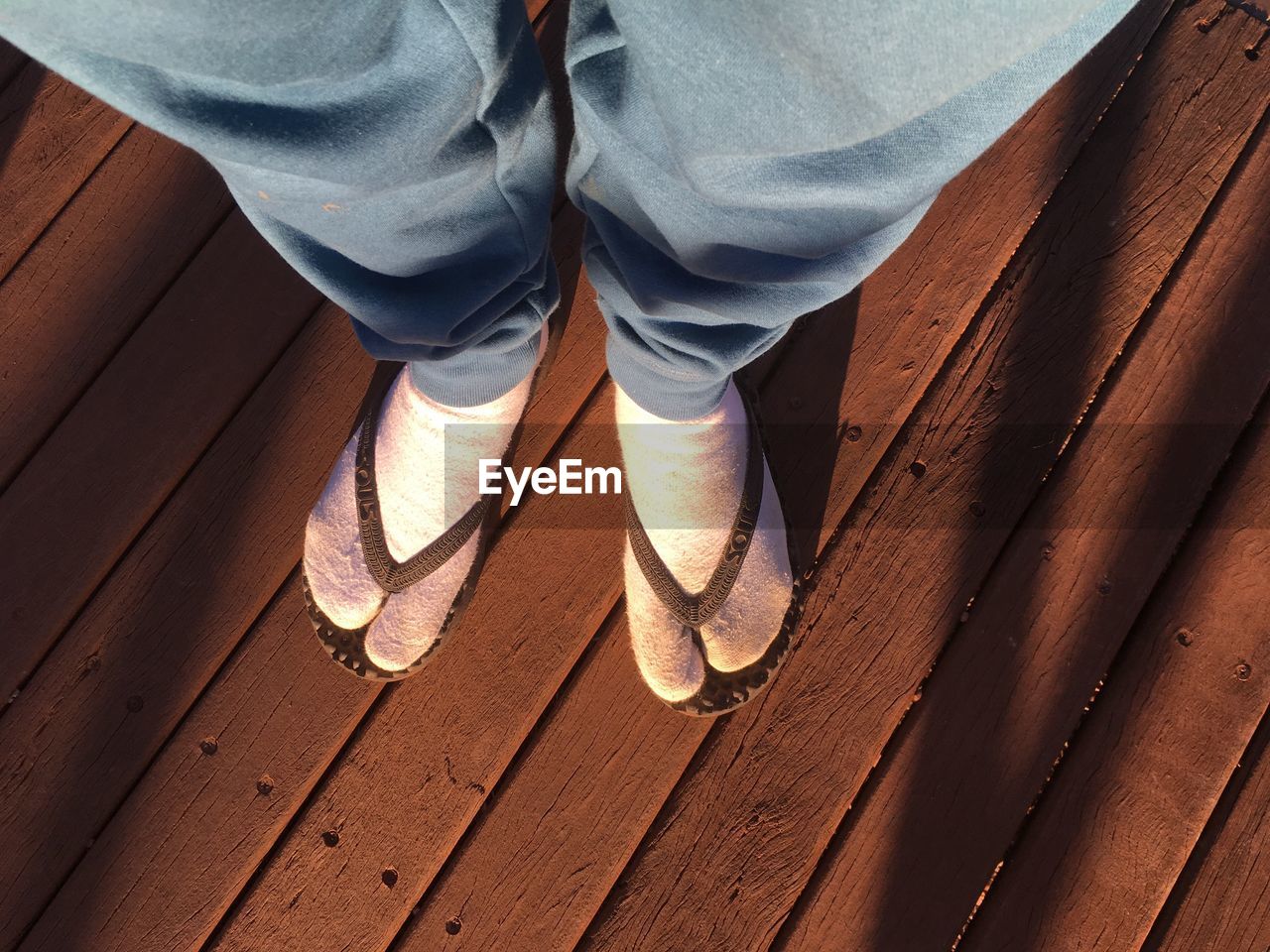 Low section of man standing on wooden walkway