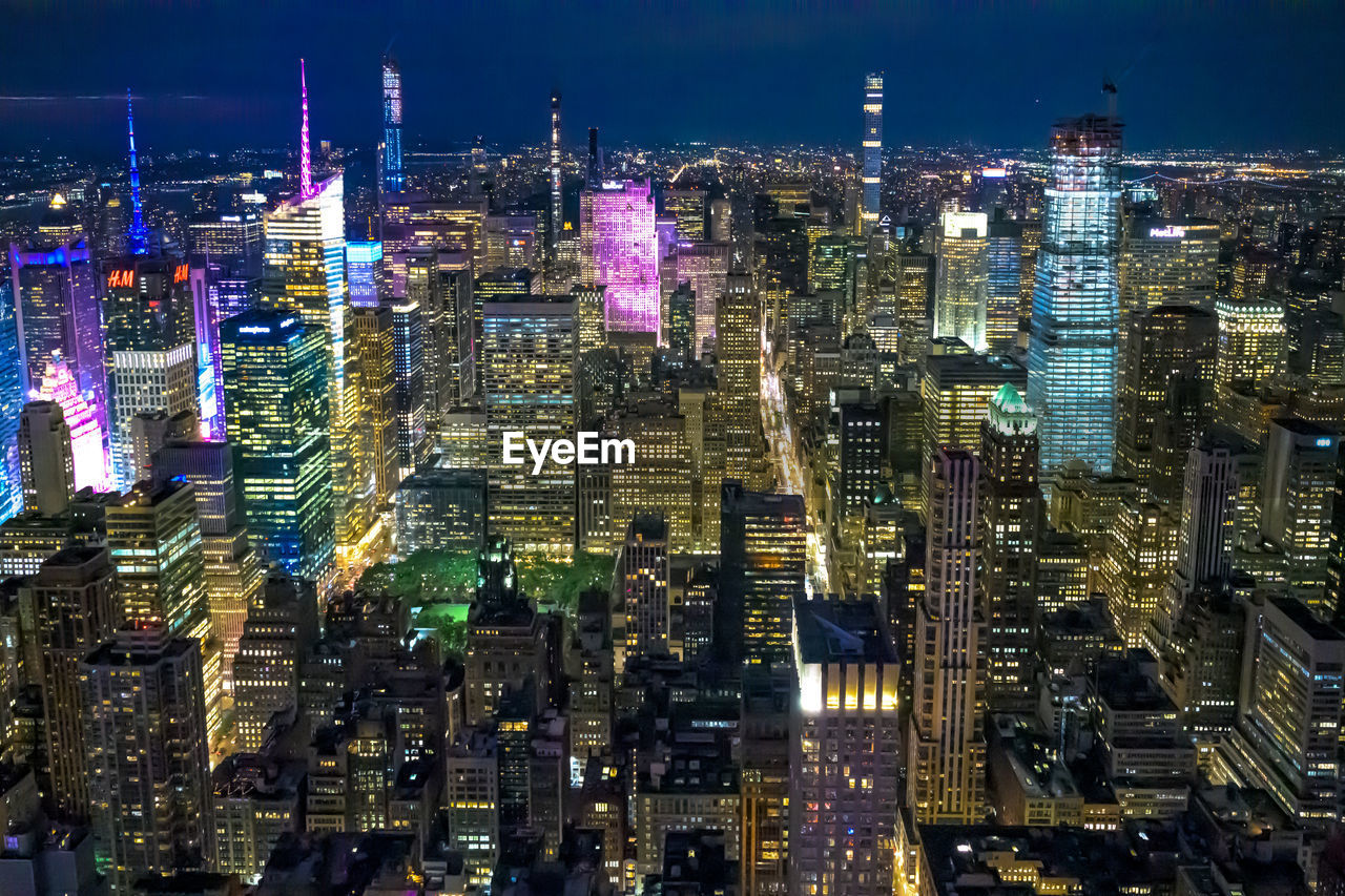 HIGH ANGLE VIEW OF ILLUMINATED MODERN BUILDINGS IN CITY