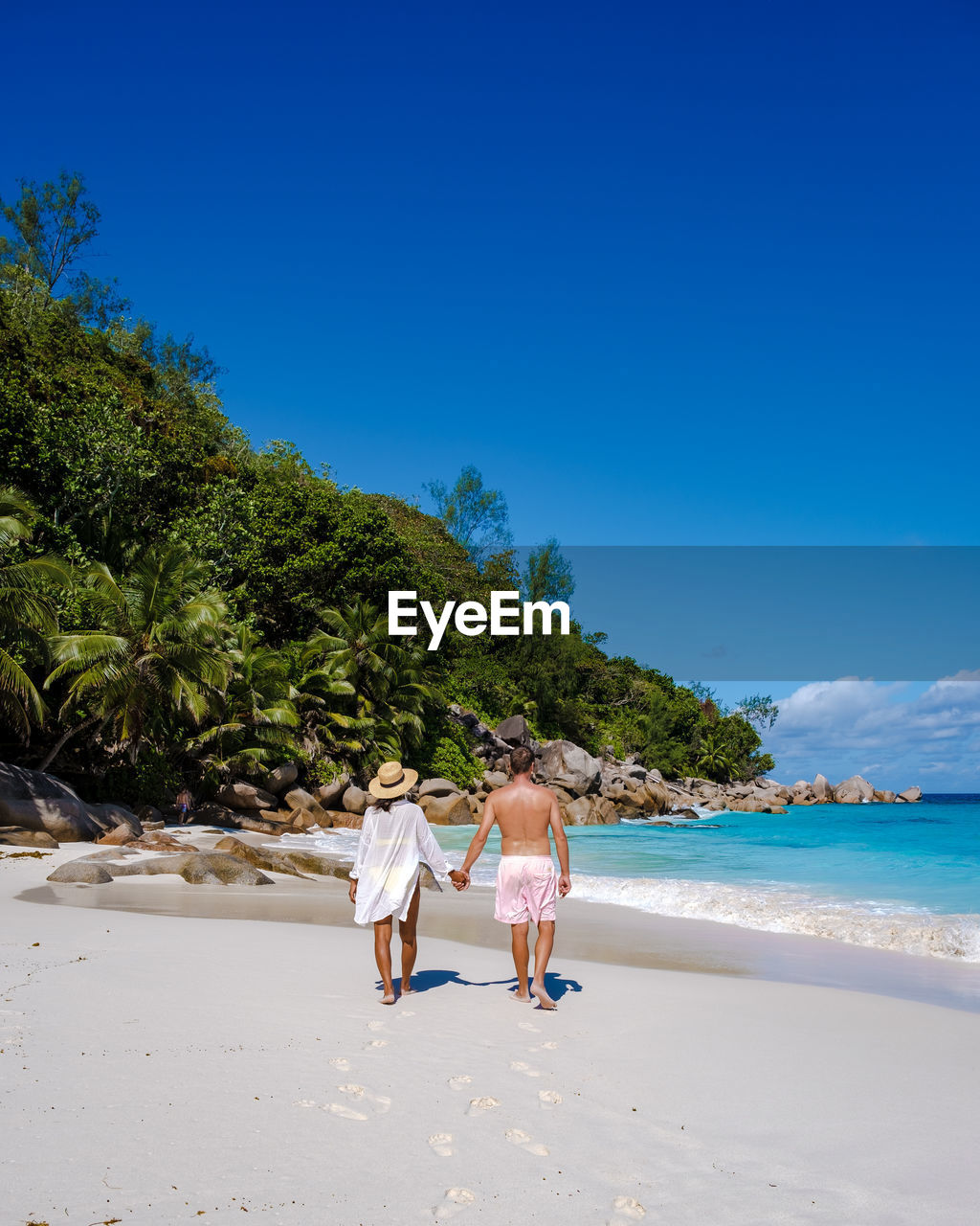 rear view of woman standing at beach against clear blue sky