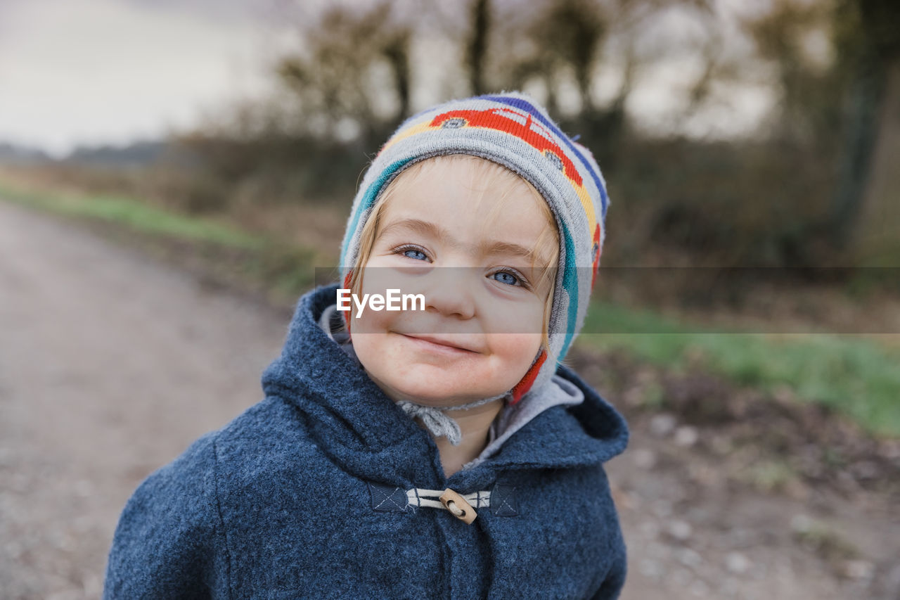 Portrait of cute girl standing on road during winter