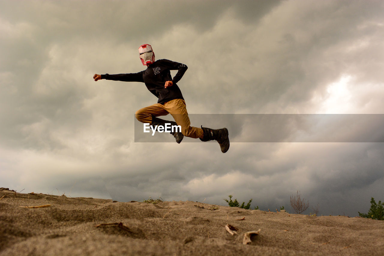 MAN JUMPING AGAINST CLOUDY SKY