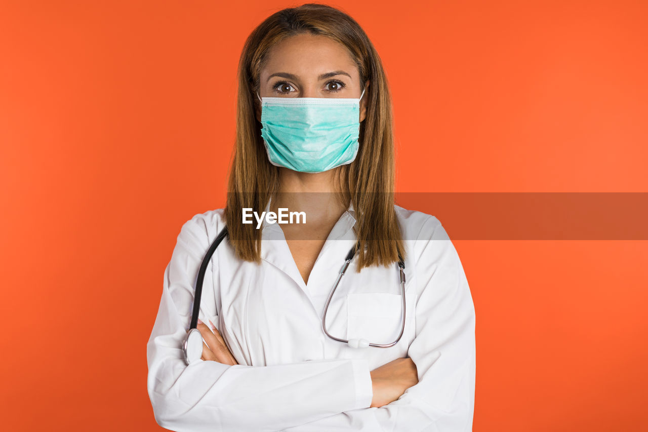 portrait of young woman wearing protective mask against yellow background