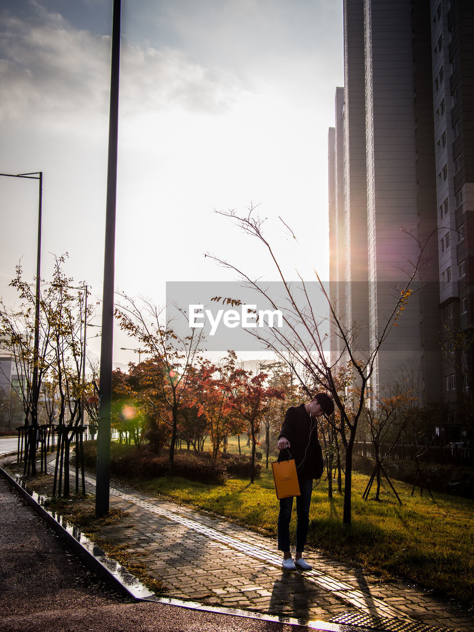 WOMAN STANDING BY TREE IN CITY