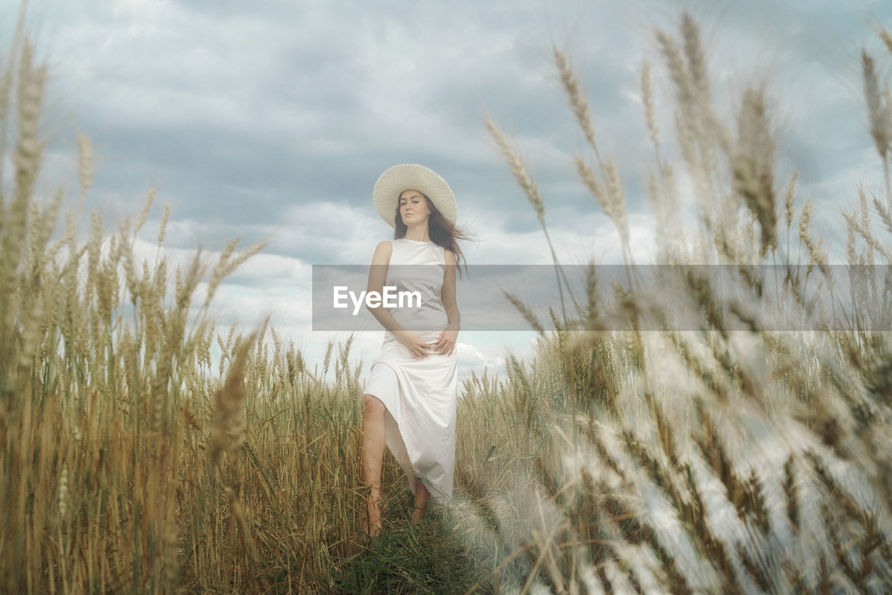 Young woman on field against sky