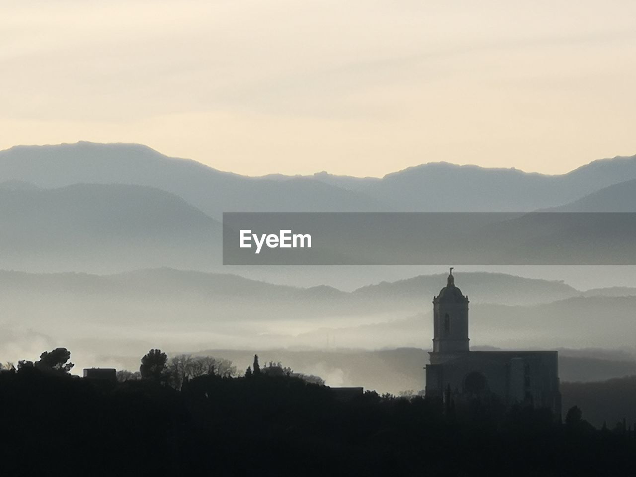 Silhouette of building and mountains against sky