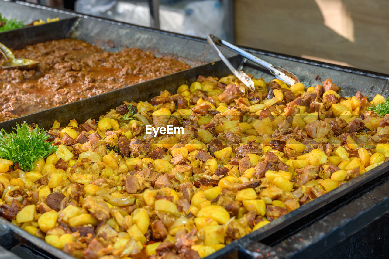 Chicken and potatoes in large tray on street food stall in budapest, hungary