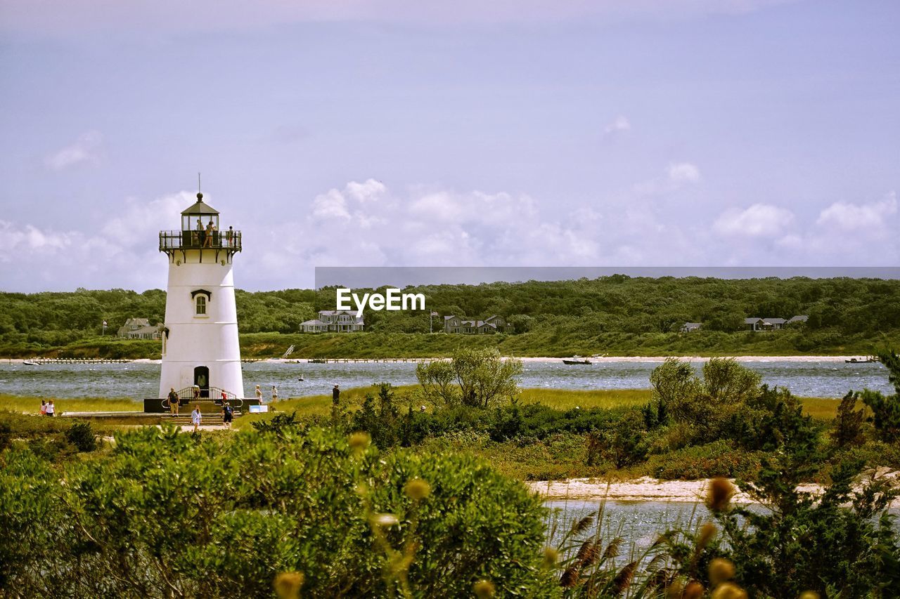 Lighthouse by building against sky