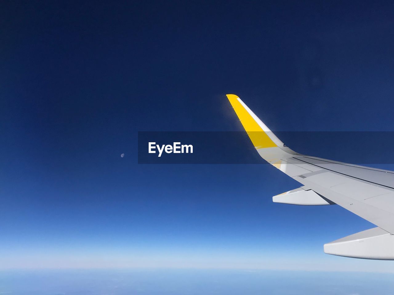 Cropped image of airplane wing flying against clear blue sky