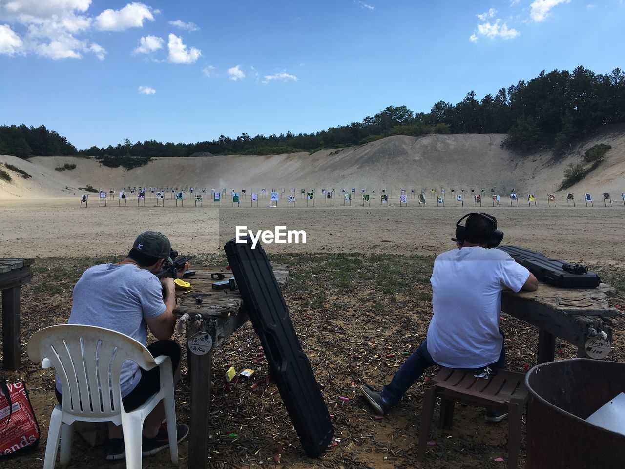 Rear view of fiends practicing with rifle at shooting range