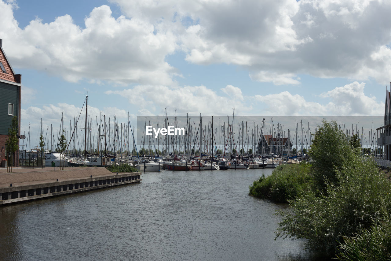 VIEW OF BOATS MOORED AT HARBOR AGAINST CLOUDY SKY