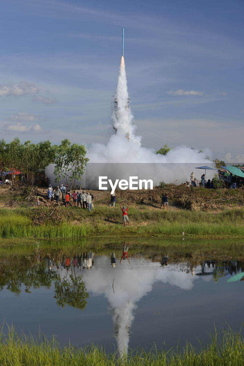 Group of people watching rocket launch on landscape