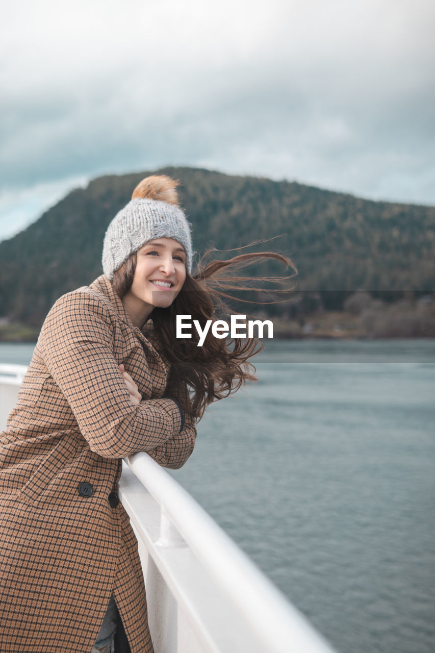 Woman wearing warm clothing standing in boat on sea