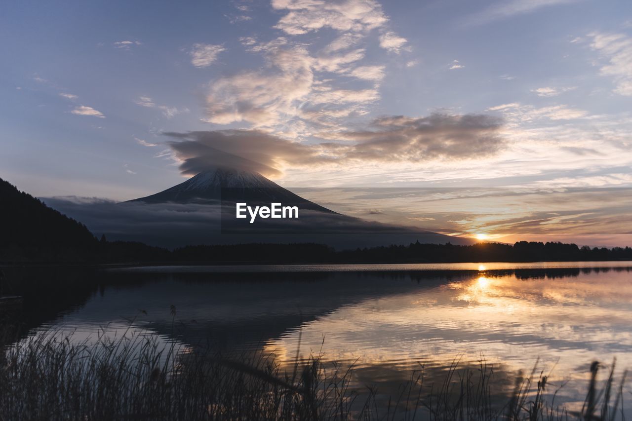 Scenic view of lake and mountain against sky at sunset