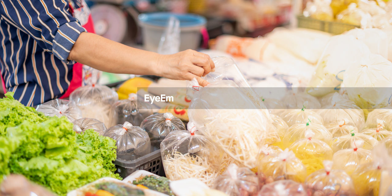 The female hand seller arranges the packaging of vegetables on the shelf and preparing to sell.