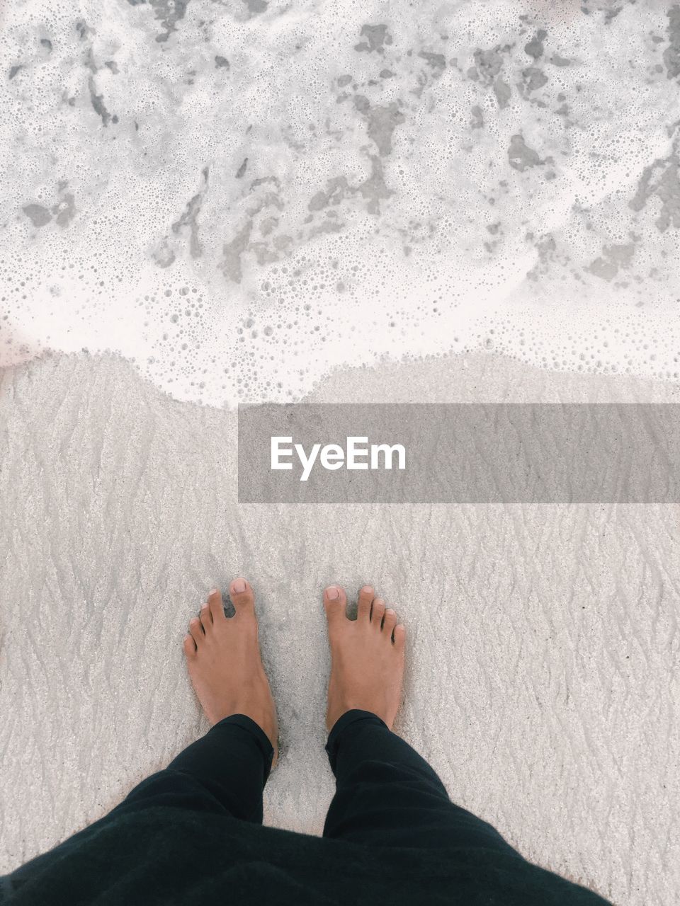 Low section of man standing at beach