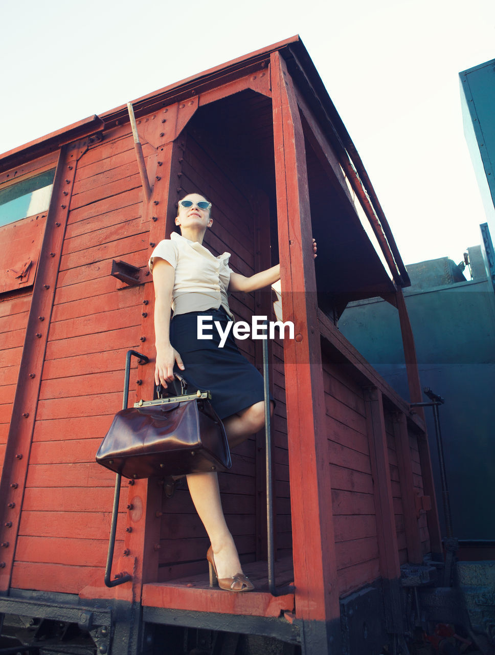 Low angle portrait of woman against clear sky