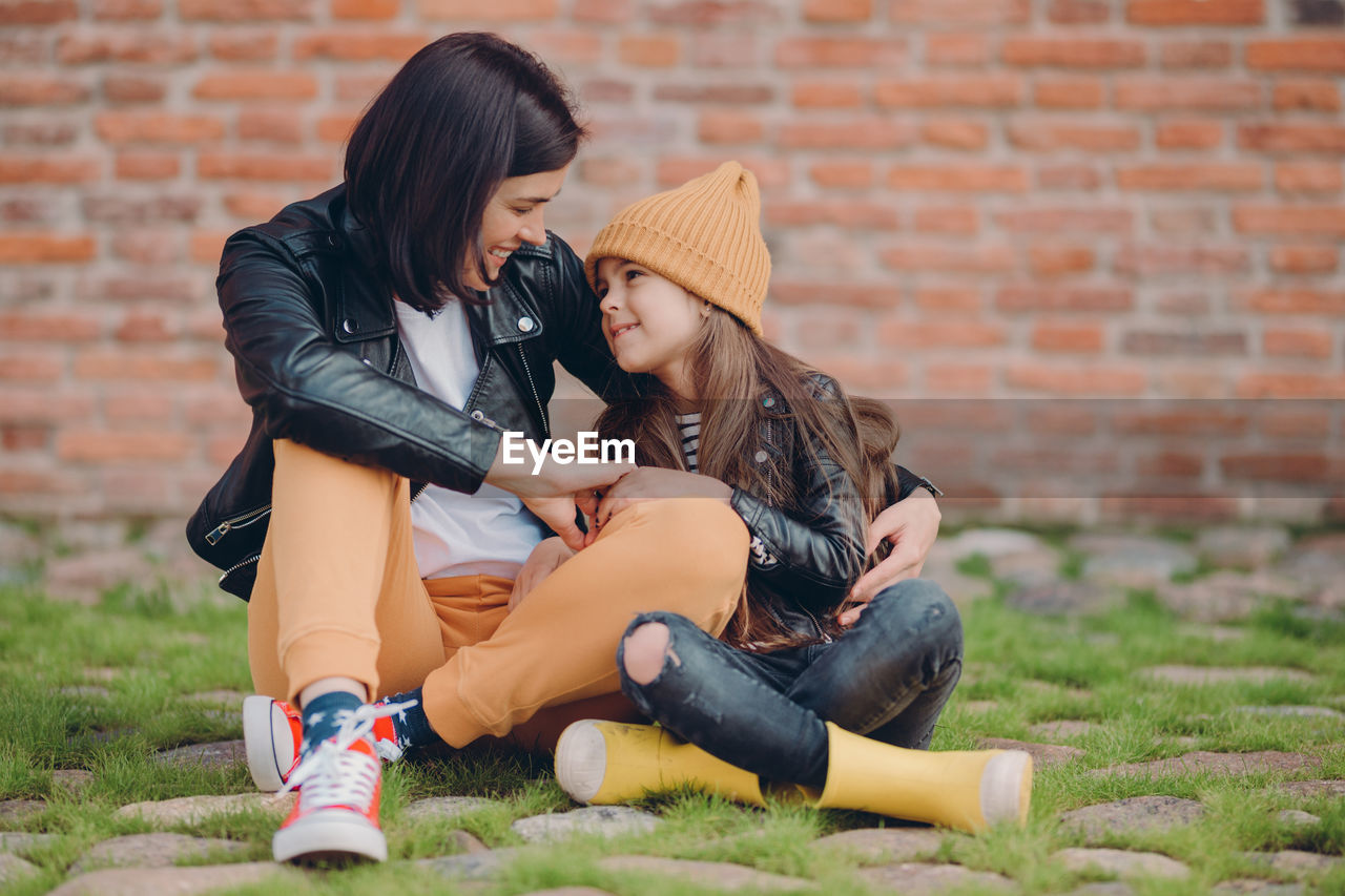 Full length of mother and daughter sitting outdoors