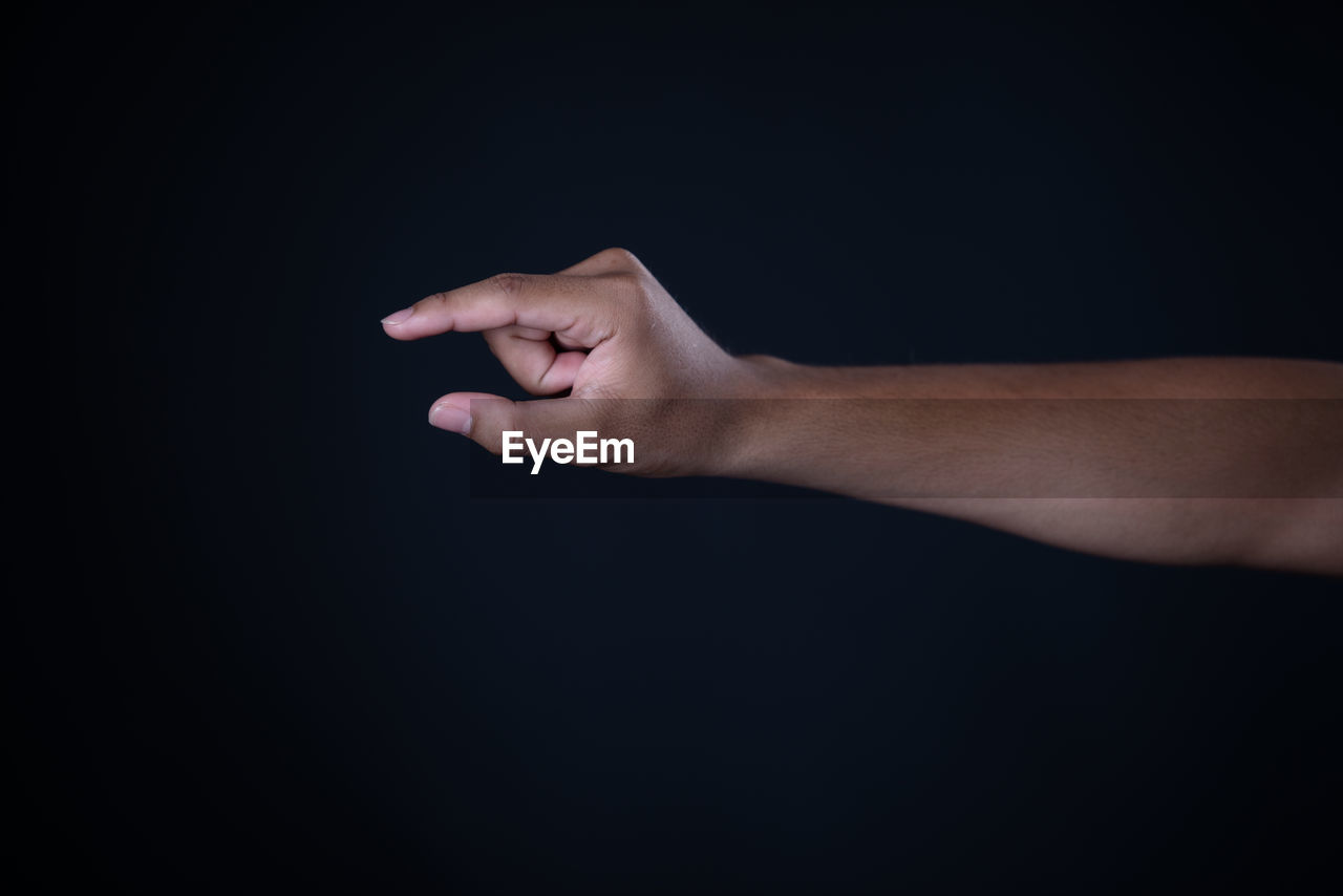 CLOSE-UP OF HAND AGAINST BLACK BACKGROUND