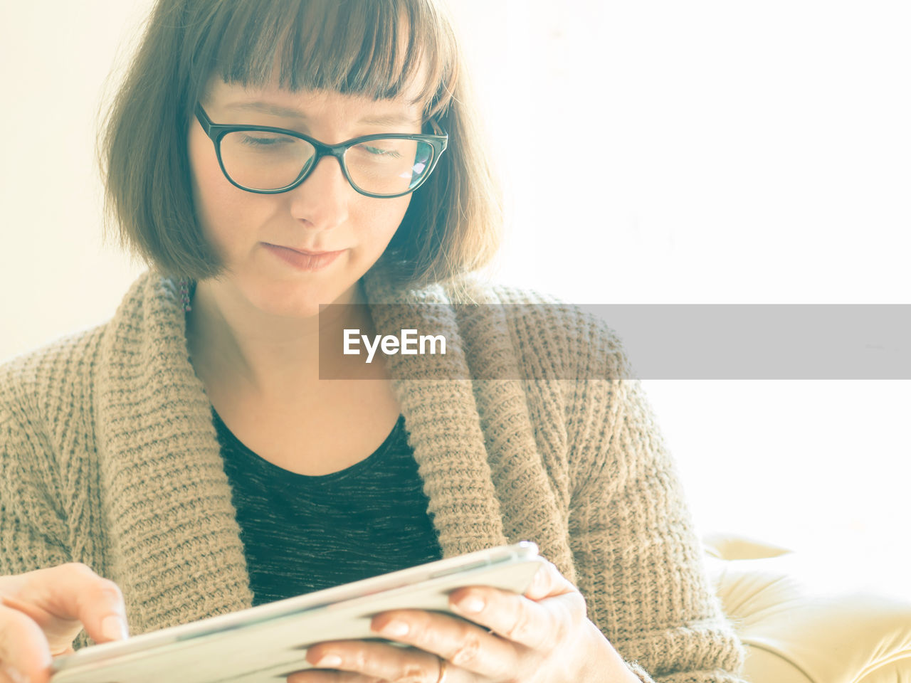 Close-up of mid adult woman using digital tablet against window at home