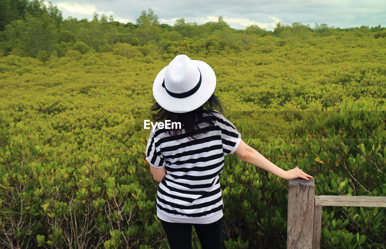 Rear view of woman wearing hat standing on field