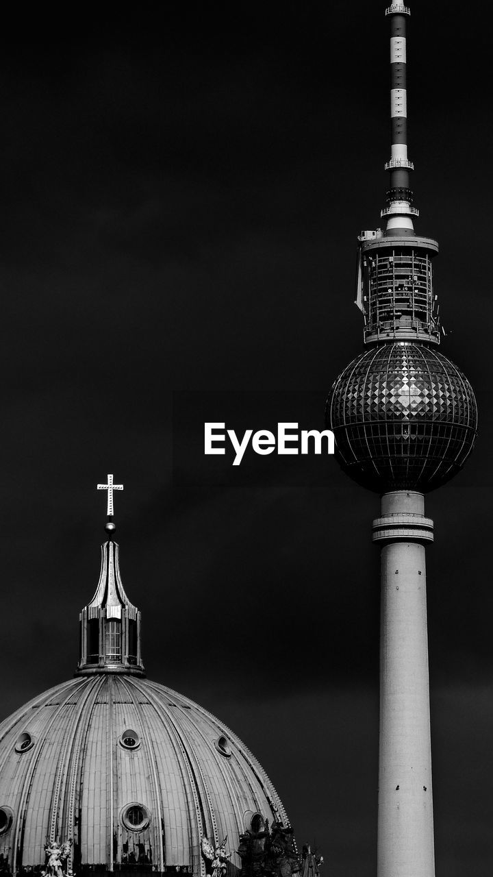 Low angle view of communications tower in city against sky