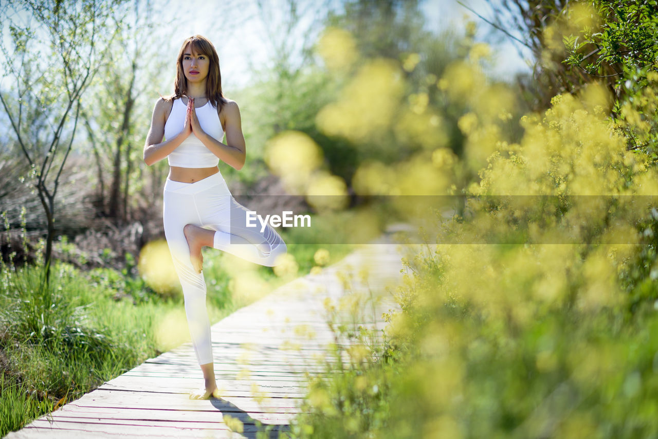 Beautiful mid adult woman doing yoga on boardwalk