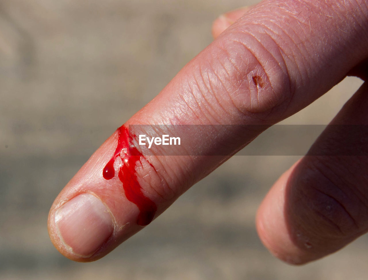 CLOSE-UP OF HUMAN HAND HOLDING RED BLURRED BACKGROUND