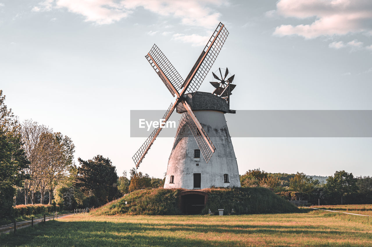 Traditional windmill on field against sky