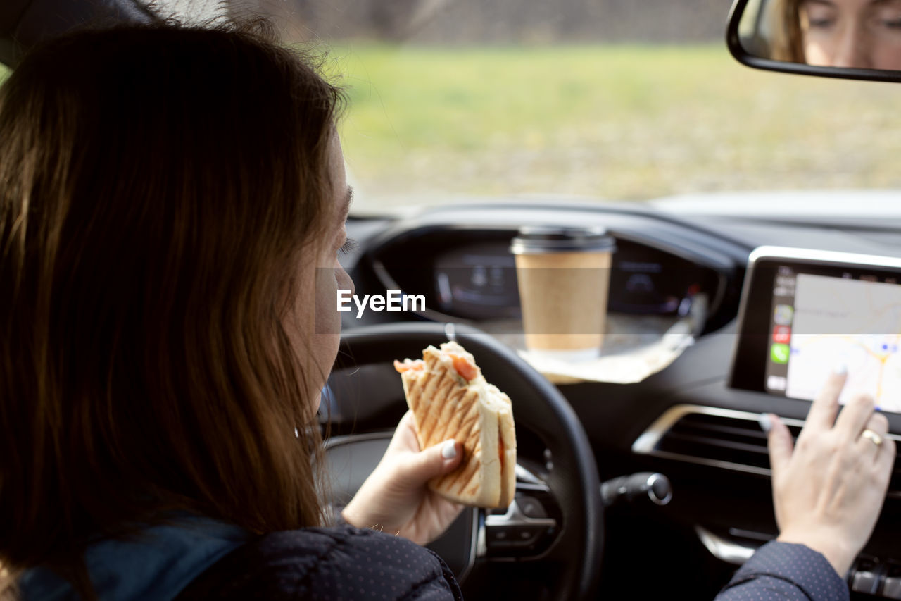 Drive-in lunch woman sitting car eating take away coffee