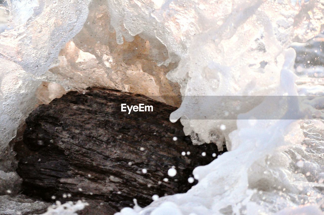 CLOSE-UP OF ICE ON ROCK AGAINST MOUNTAIN