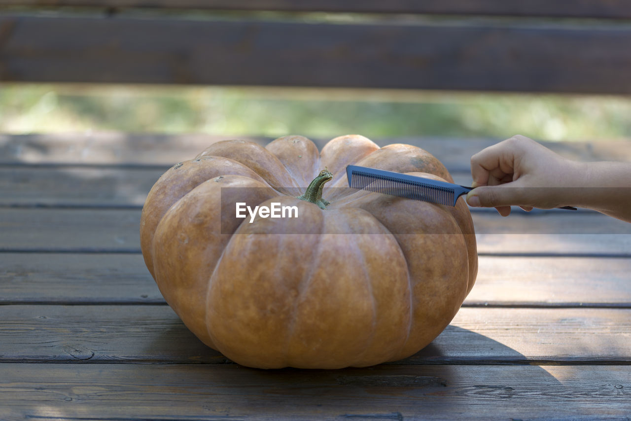 Close-up of hand holding pumpkin on table