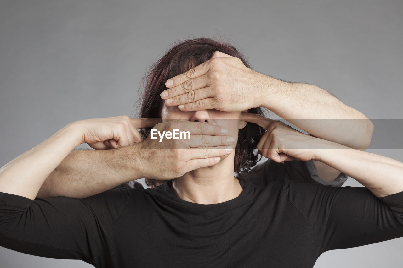 Cropped image of hand covering woman eyes against white background