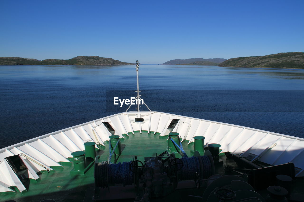 Cropped image of boat overlooking blue sea and mountains against clear sky