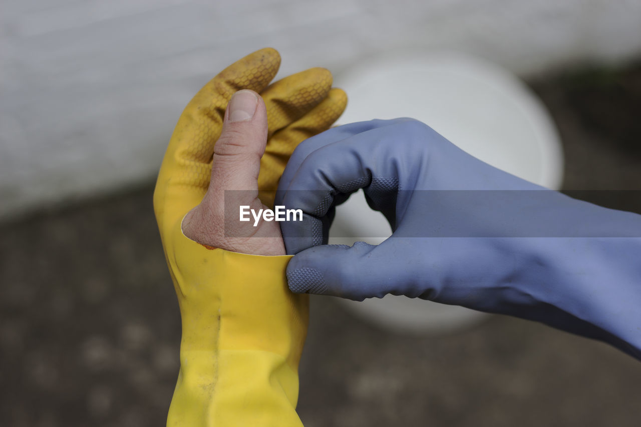 Close-up of man's hand wearing broken yellow gloves