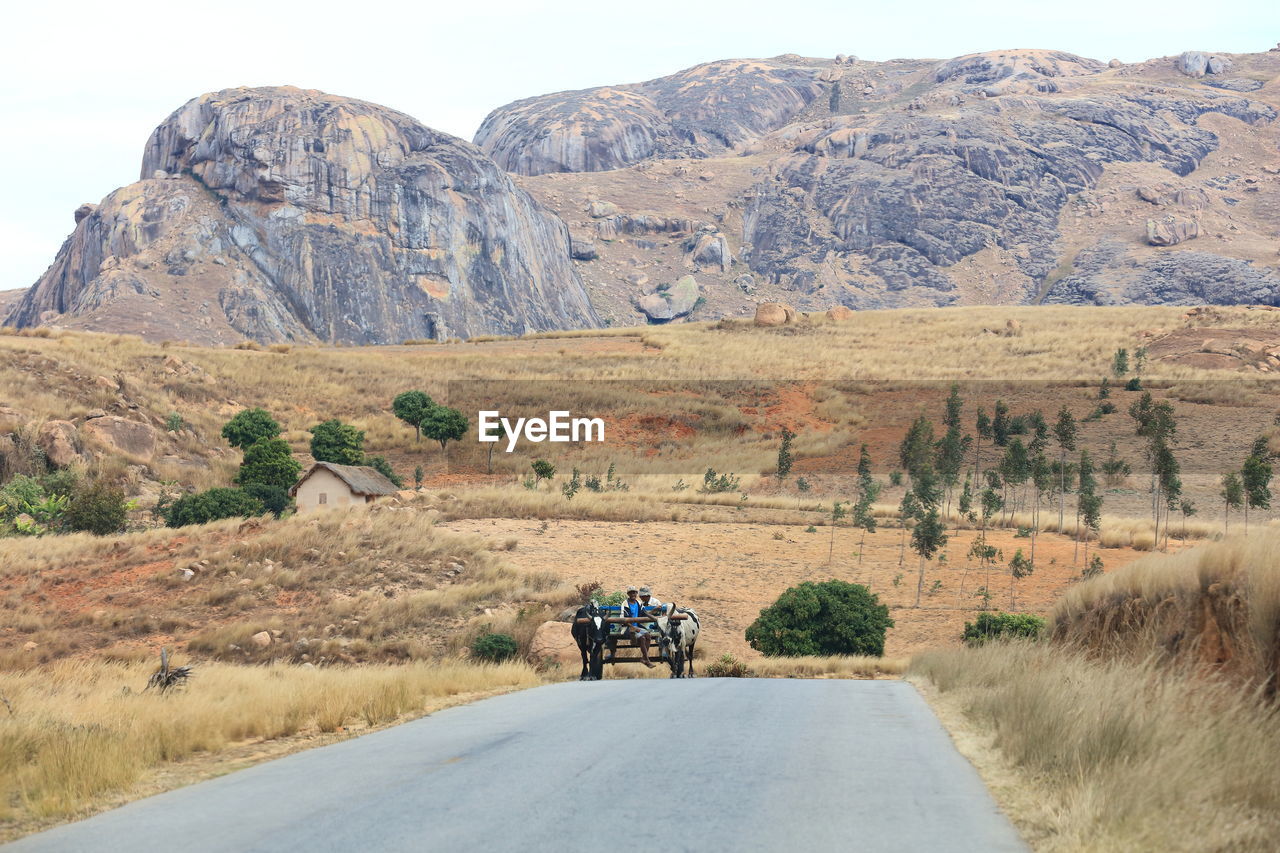 REAR VIEW OF MAN ON ROAD AGAINST MOUNTAINS
