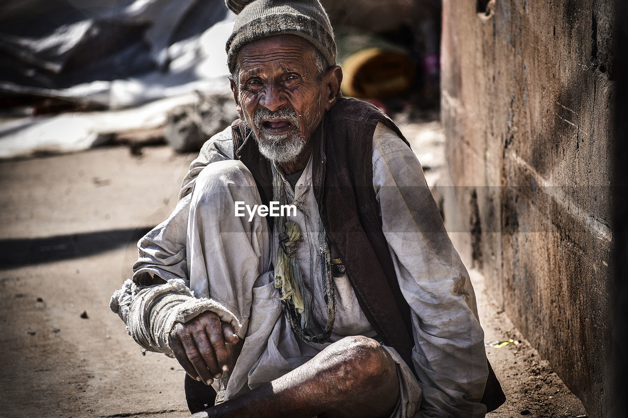 Portrait of beggar sitting on footpath